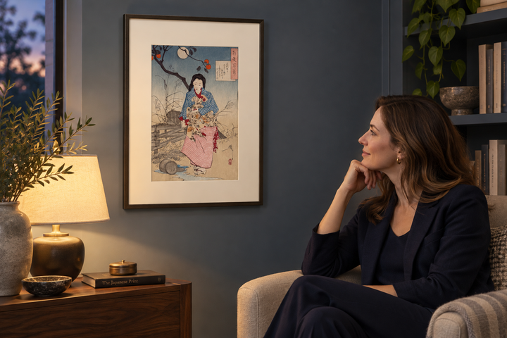 A woman seated beside a framed Yoshitoshi print of Chiyono on a blue wall in a lamplit reading corner.