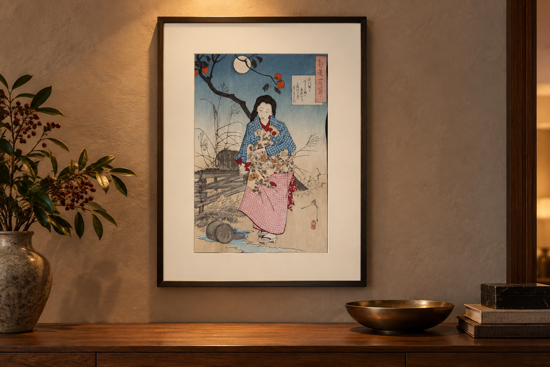 The framed Yoshitoshi print of Chiyono above a wooden console with a vase, shallow bowl, and books in warm evening light.