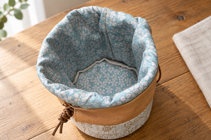 Open natural leather Edo Komon pouch viewed from above, showing its pale blue patterned lining and round base.