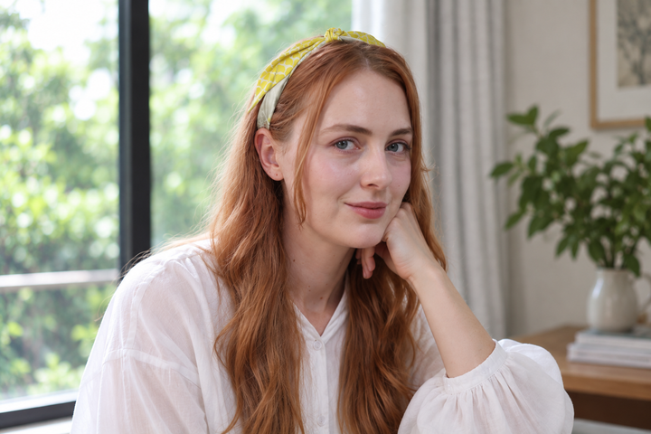 A narrow yellow and grey-green silk scarf folded as a slim hair band in soft window light.