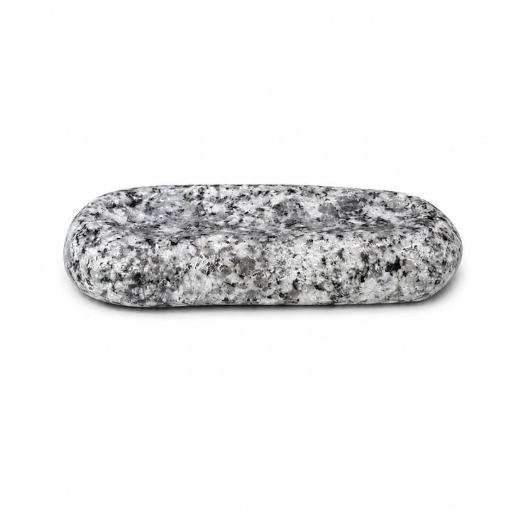 Makabe Stone Cutlery Rest on a pure white background, showing its rounded granite form and shallow groove.