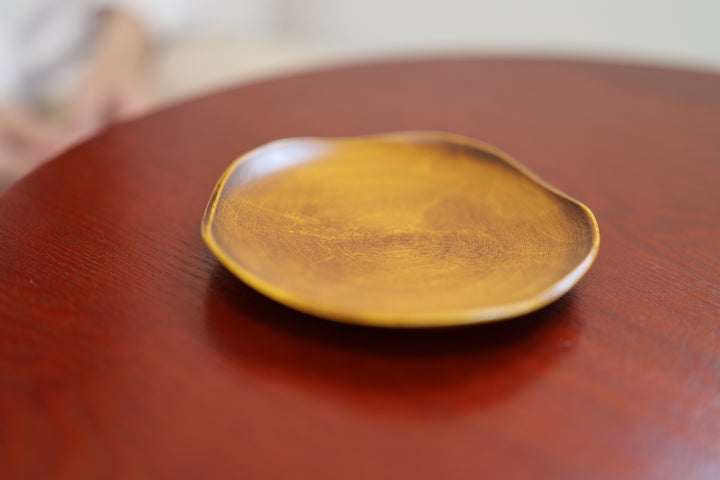 RIN 5.0 Mimosa plate on a warm reddish-brown tabletop with a softly blurred arm in the background.