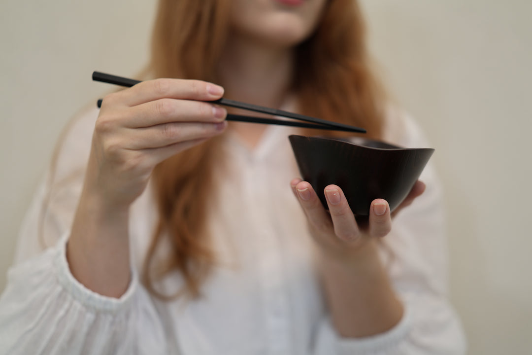 Adult model holding the empty RIN Bowl M Lilac with chopsticks above its undulating rim.