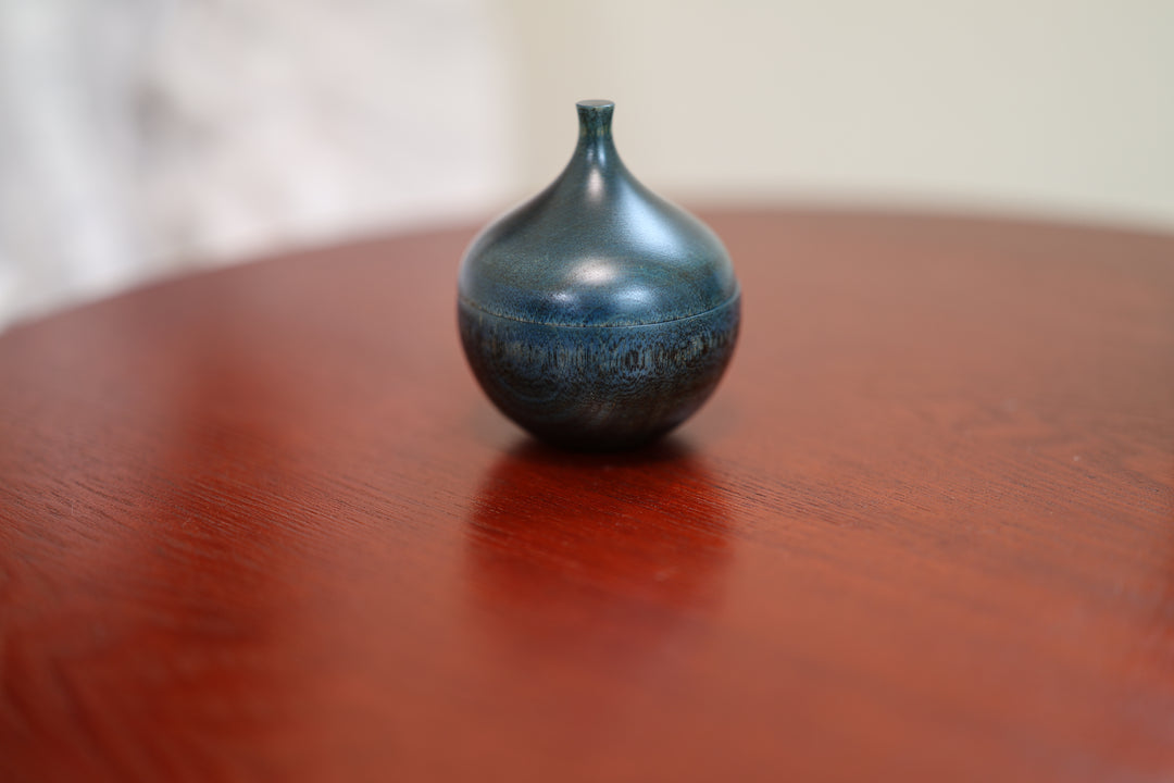 Closed Bulb: Hyacinth lacquerware resting alone on a warm red lacquered table.