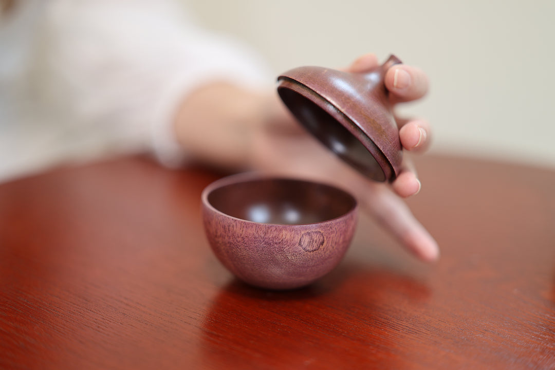 The open lilac lid beside the rounded wooden body on a table