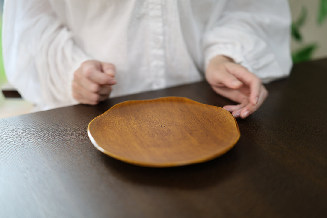 Empty RIN 7.0 Mimosa plate on a dark table in front of a seated adult model.