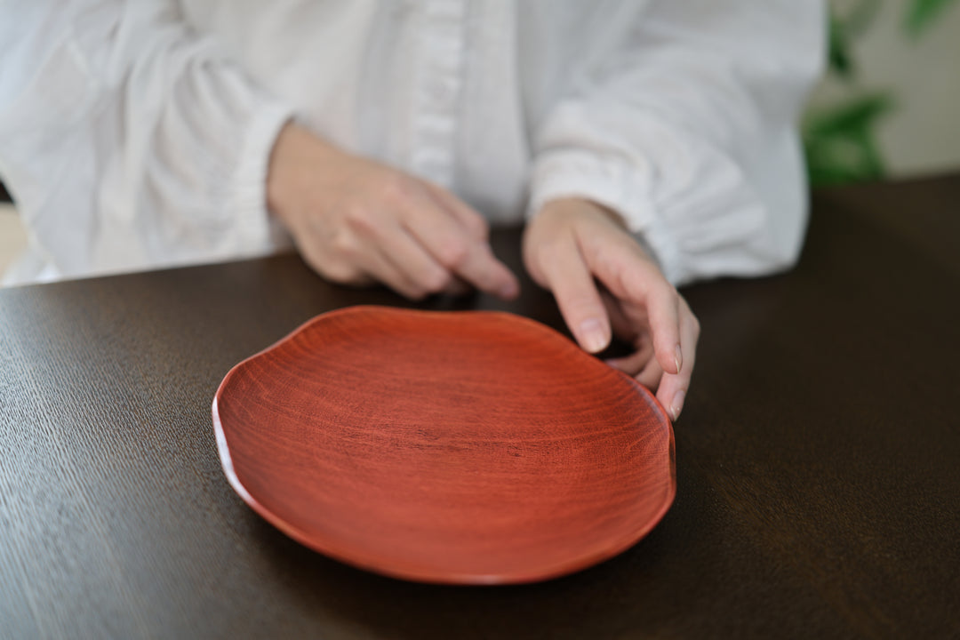 Hands beside a berry-red RIN plate on a dark wooden table