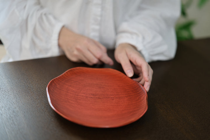 Hands beside a berry-red RIN plate on a dark wooden table