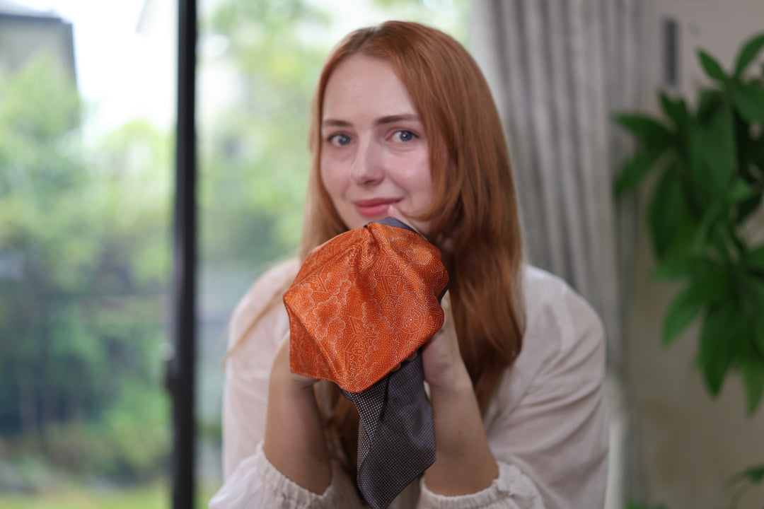 Front-facing portrait with the model holding the patterned silk square close to the camera.