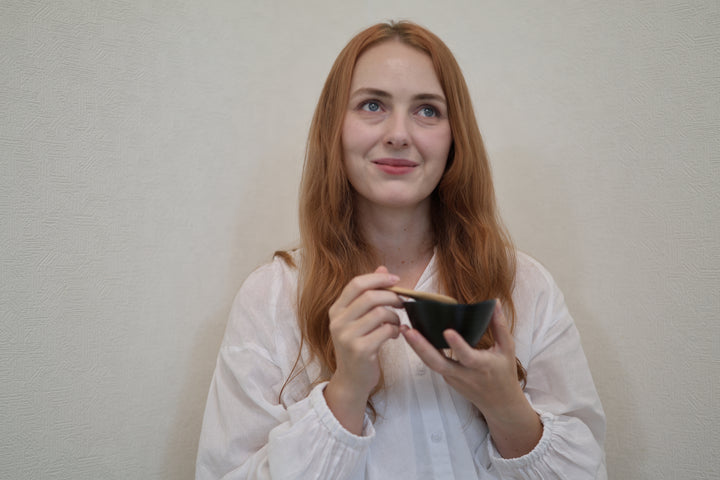 Adult model holding the small RIN Bowl S Hyacinth and a wooden spoon against a plain interior wall.
