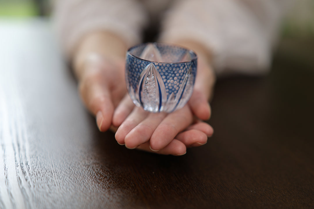 GENEN Indigo cut-glass vessel resting on two open hands.