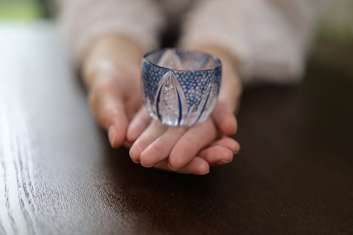 GENEN Indigo cut-glass vessel resting on two open hands.