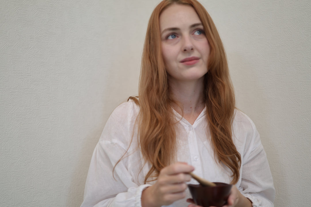 Adult model holding the small RIN Bowl S Lilac at waist height against a plain interior wall.
