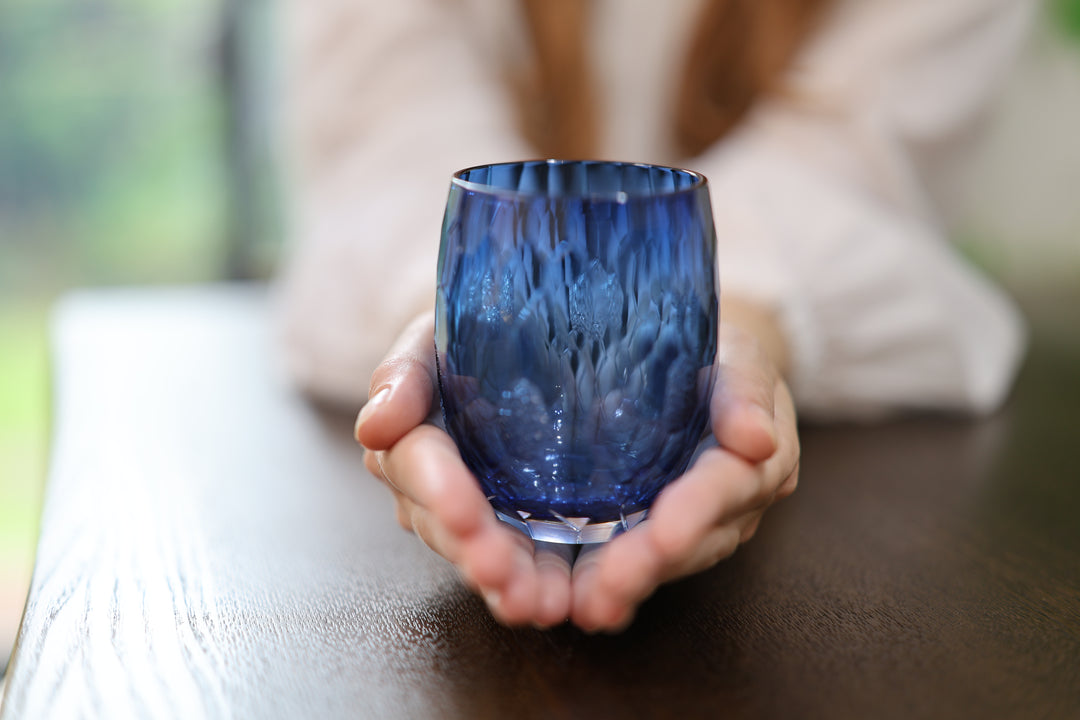 Indigo Edo Kiriko glass presented upright in two open hands