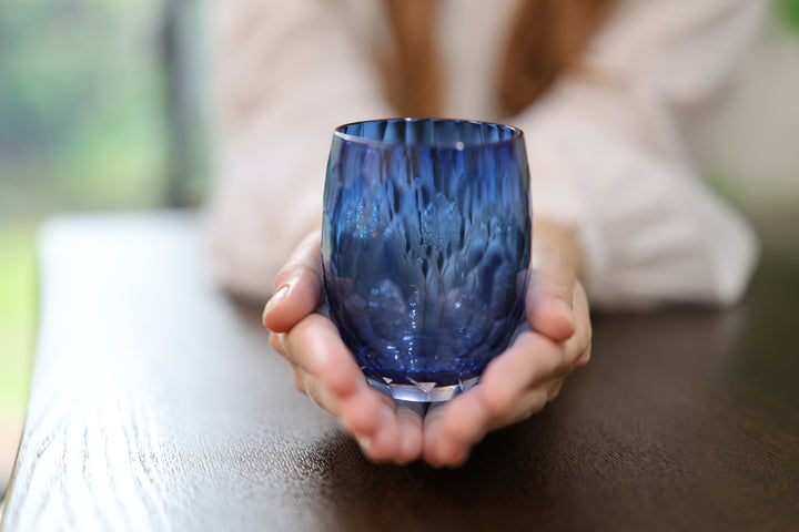 Indigo Edo Kiriko glass presented upright in two open hands