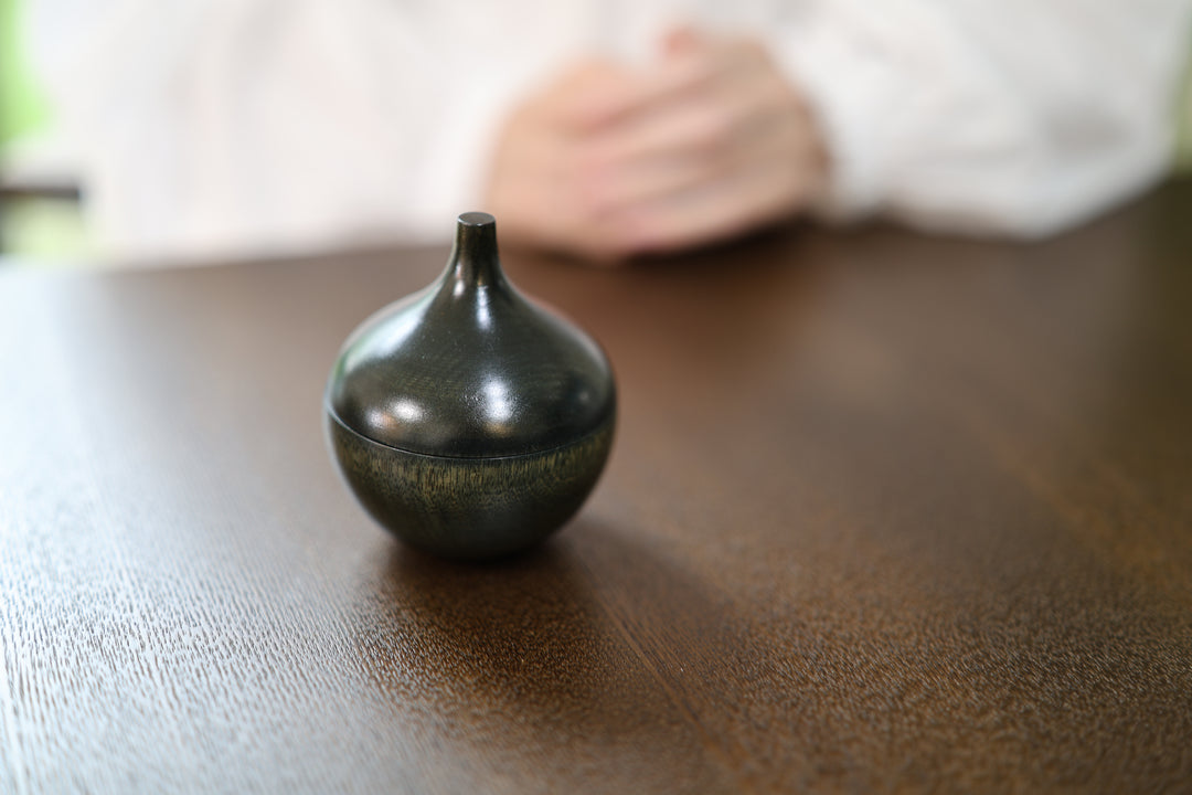 Bulb: Sesame closed on a dark tabletop in a softly lit interior.