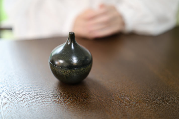 Bulb: Sesame closed on a dark tabletop in a softly lit interior.