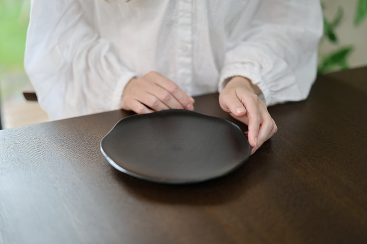 Two hands guiding the RIN 7.0 Sesame on a dark tabletop while its center remains visible.