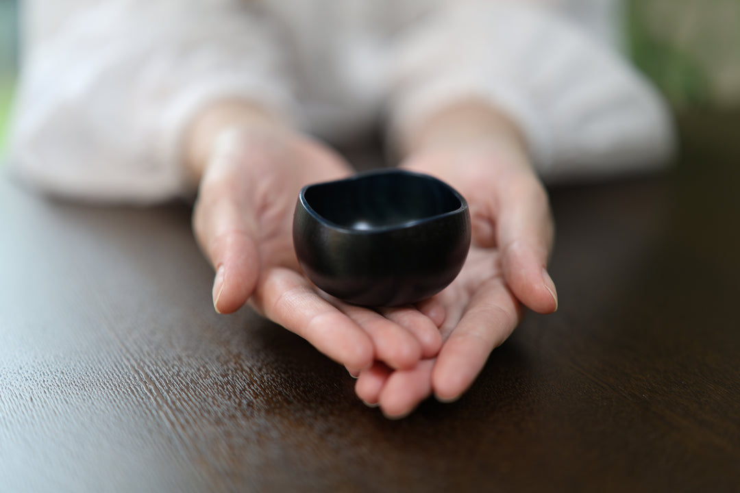 Close view of the Bud: Hyacinth lacquered vessel resting in two hands