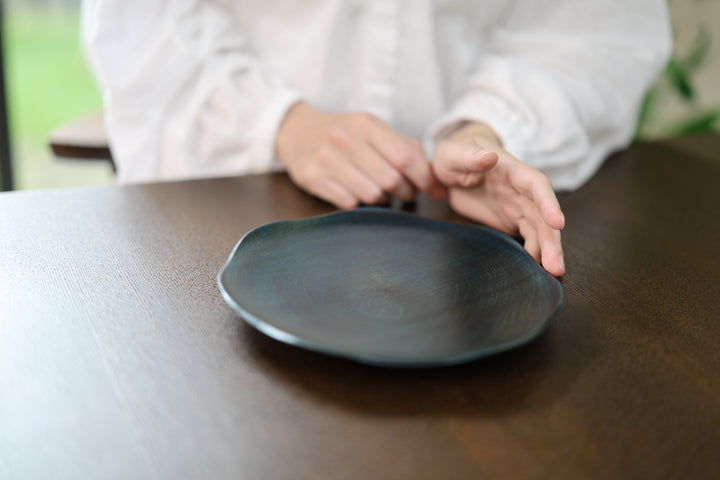 Two hands guiding the RIN 7.0 Hyacinth on a dark tabletop while its center remains visible.