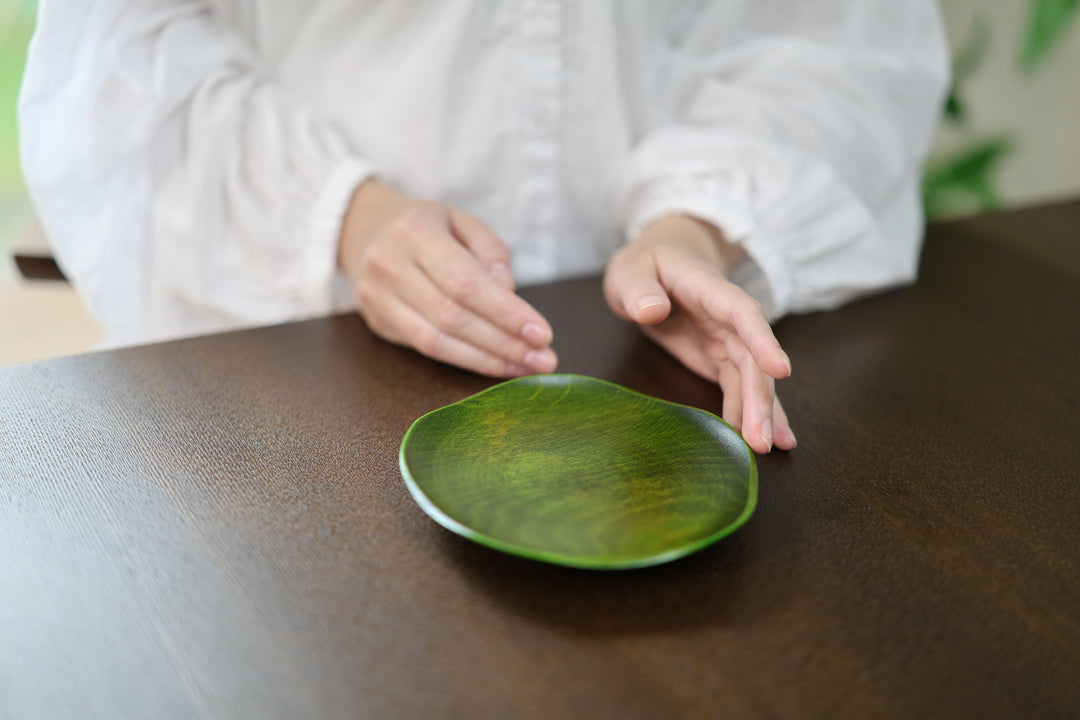 The RIN 5.0 Olive plate centered on a dark table between the hands of a seated person.