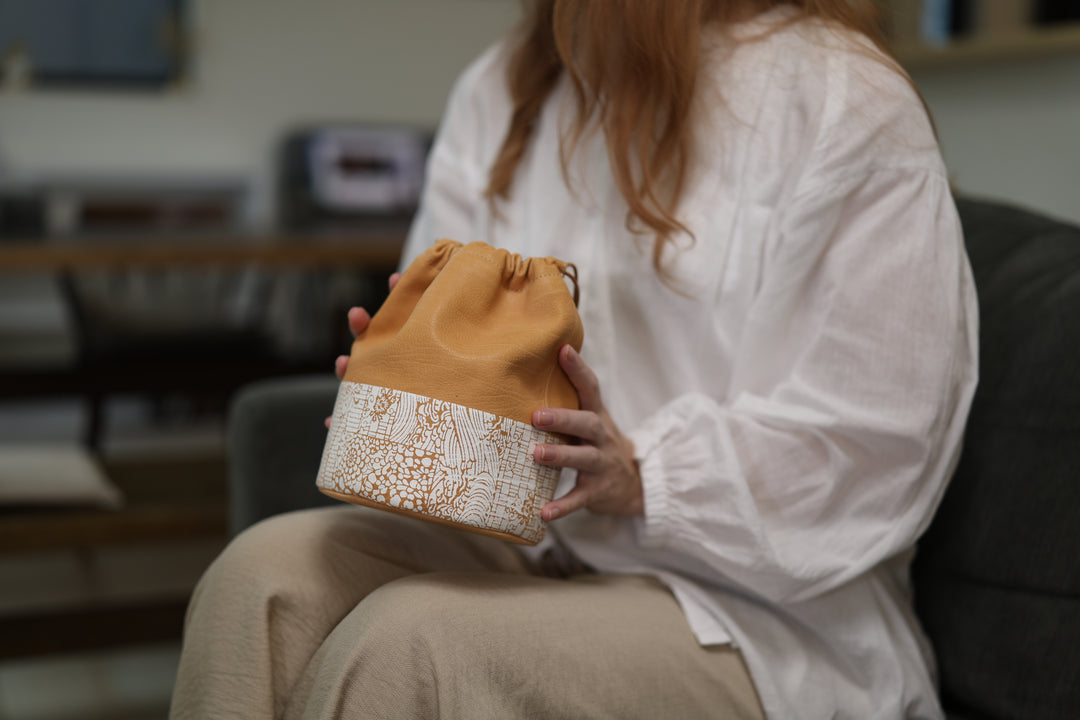 Natural leather pouch resting on a lap in a quiet living room.