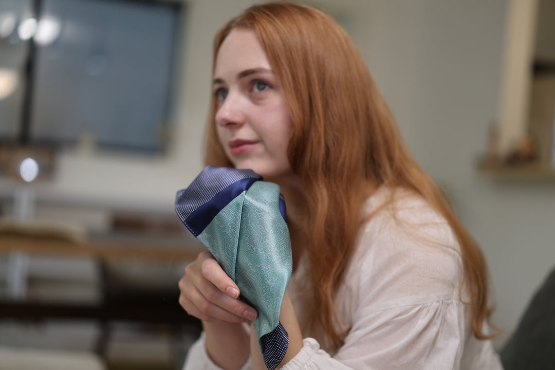 Side view of a model holding the silk pocket square in a softly lit interior.