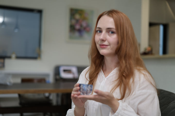 Adult presenting the GENEN Indigo cut-glass vessel in an interior.