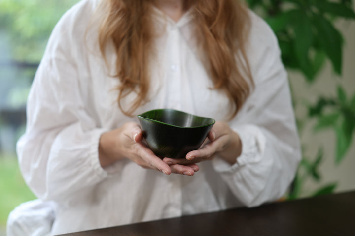 Adult model supporting the RIN Bowl M Olive in both hands near a window.
