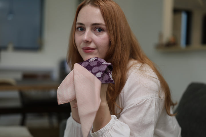 Close indoor view of a person holding the two-color silk pocket square across both hands.
