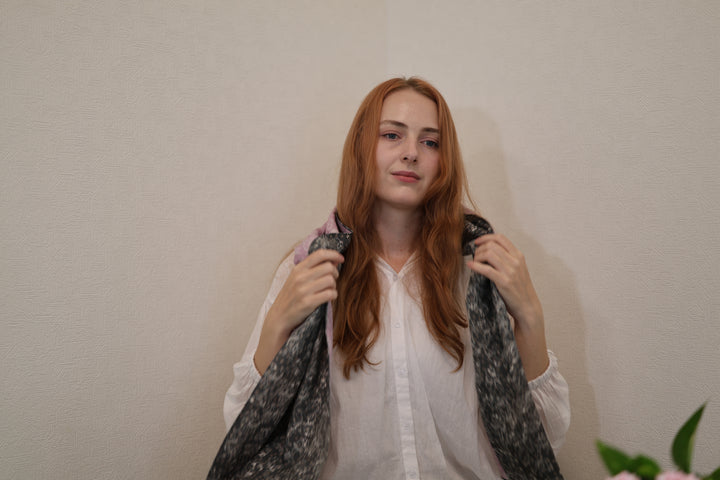 Model holding both ends of the purple and black reversible sumo-pattern stole indoors
